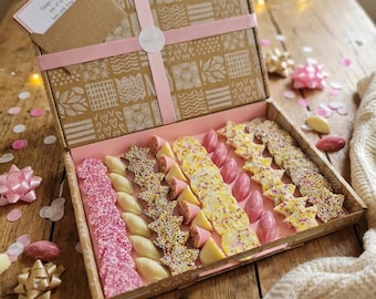 May include: A rectangular cardboard gift box with a patterned lid, tied with a pink ribbon, containing an assortment of pink, white, and yellow star-shaped and round chocolates with sprinkles. A small card reads: Happy Birthday lots of love Sam and Amy.