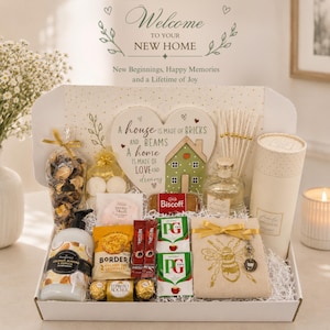 May include: A gift box containing a heart-shaped sign with the text A house is made of bricks and beams a home is made of love and dreams, coconut almond handwash, Biscoff biscuits, Border cookies, Nescafé coffee, PG Tips tea, a bee-print cloth, and a candle.