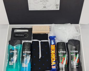 May include: A gift box containing two Lynx Ice Chill body wash and spray bottles, two Lynx Africa body wash and spray bottles, a pair of black socks with blue squares, a Yorkie chocolate bar, a nail clipper, a keychain, a brush, and a white loofah.