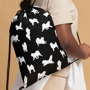 Può includere: Borsa a sacco nera con un motivo a silhouette bianca di cani lapponi finlandesi. La borsa ha un cordoncino nero e spalline nere.
