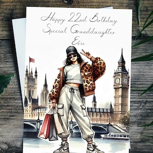 May include: A birthday card with a watercolor illustration of a woman in a leopard print jacket and white pants holding shopping bags in front of Big Ben and the Houses of Parliament. The card says "Happy 22nd Birthday Special Granddaughter Evie".