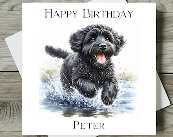 May include: A square greeting card featuring a watercolor illustration of a fluffy black dog running through water with a splash. The text HAPPY BIRTHDAY is printed in black at the top, and the name PETER is printed in black at the bottom.