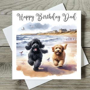 May include: Happy Birthday Dad card featuring two dogs running on a beach. The dogs are a black and brown poodle and a brown poodle. The card has a watercolour background with a beach scene and a seaside town in the distance.