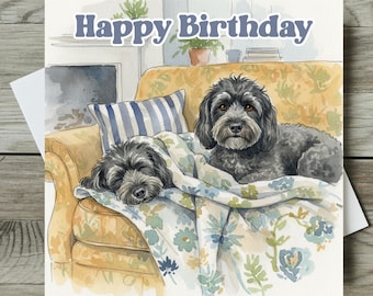 May include: Watercolor birthday card featuring two black dogs on a yellow floral couch. One dog is sleeping under a floral blanket, while the other is awake. The words "Happy Birthday" are written across the top in blue.