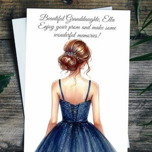 May include: A greeting card with an illustration of a woman in a navy blue prom dress. The card reads "Beautiful Granddaughter, Ella, Enjoy your prom and make some wonderful memories!" on a white background.