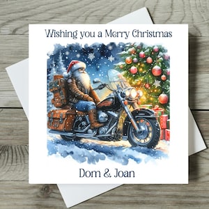 May include: A Christmas card featuring Santa Claus riding a black motorcycle with brown saddlebags. The card has the text "Wishing you a Merry Christmas" and the names "Dom & Joan". A Christmas tree and presents are in the background.