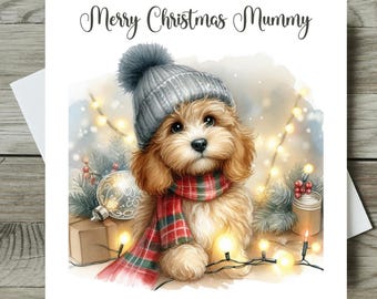 May include: A Christmas card featuring a watercolor illustration of a fluffy, light brown dog wearing a gray knit hat and a red and green plaid scarf. The card reads "Merry Christmas Mummy" in elegant script, with festive lights and ornaments.