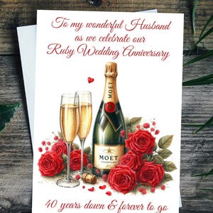 May include: A greeting card with a champagne bottle, two filled glasses, and red roses. The card reads "To my wonderful Husband as we celebrate our Ruby Wedding Anniversary" and "40 years down & forever to go."