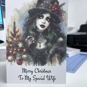 K&ouml;nnte beinhalten: Weihnachtskarte mit einer gotischen Illustration einer Frau mit Zylinder und Pelz. Auf der Karte steht "Merry Christmas To My Special Wife". Das Bild zeigt einen Weihnachtsbaum mit Ornamenten und Kerzen.