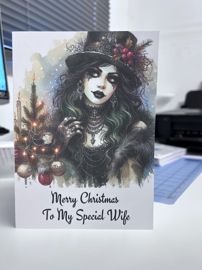 K&ouml;nnte beinhalten: Weihnachtskarte mit einer gotischen Illustration einer Frau mit Zylinder und Pelz. Auf der Karte steht "Merry Christmas To My Special Wife". Das Bild zeigt einen Weihnachtsbaum mit Ornamenten und Kerzen.
