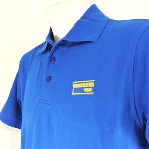 May include: A royal blue polo shirt with a yellow embroidered logo that says "Blockbuster Video".