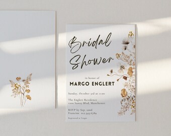 May include: A white bridal shower invitation with a floral design in shades of brown and white. The text reads "Bridal Shower" in a handwritten font, followed by "in honor of MARGO ENGLERT". The invitation includes the date, time, location, and RSVP information.