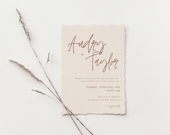 May include: A wedding invitation with a rustic, cream-colored paper texture. The names "Audrey + Taylor" are written in a cursive script in brown ink. The invitation details the date and time of the wedding ceremony, which is Sunday, February 4th at 11:00 am at Hilltop Gardens.