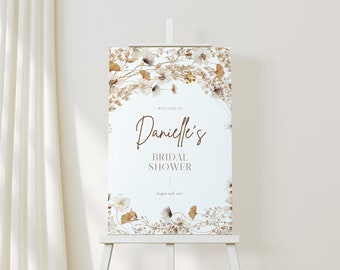 May include: A white welcome sign with a brown floral border. The text reads "Welcome to Danielle's Bridal Shower August 27th, 2023".