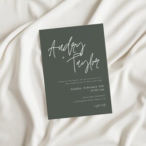 May include: A dark green wedding invitation with white calligraphy that reads "Audrey + Taylor". The invitation details the date and time of the wedding, Sunday, February 4th at 11:00 am, and the location, Hilltop Gardens, 115 Brighford LN,  Martie IL.