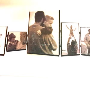 May include: A multi-panel photo frame set with black frames. The frames display black and white photographs of people. The first frame has the text "fetco" on it. The photos depict family members in various poses.