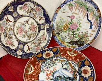 Può includere: Tre piatti in ceramica decorativi con intricati disegni floreali e di uccelli. I piatti presentano una varietà di colori, tra cui blu, rosso, oro e bianco.