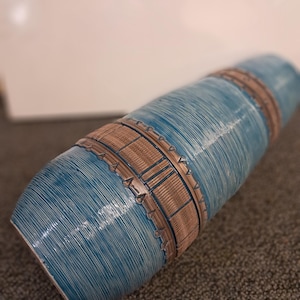 May include: A blue and brown ceramic vase with a striped pattern. The vase has a cylindrical shape and a narrow opening.