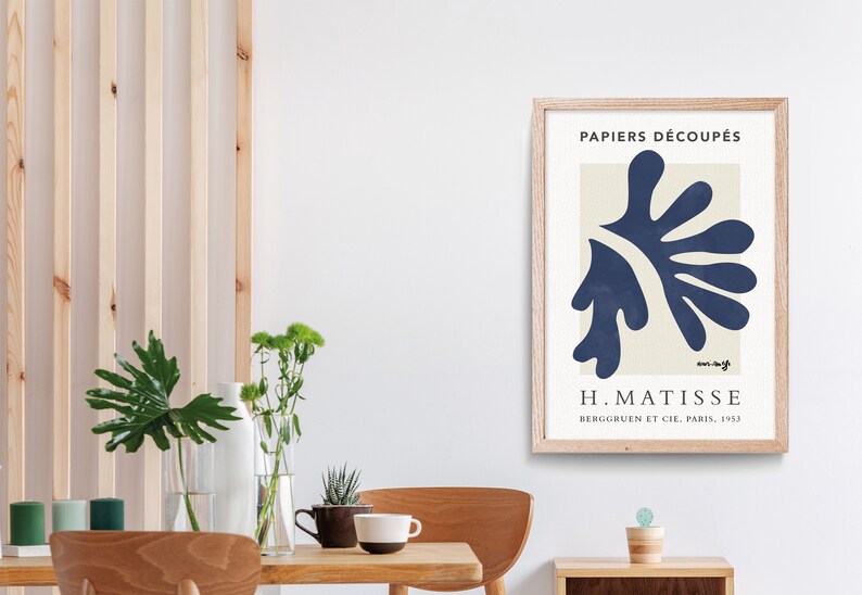 May include: A framed print of a blue abstract art piece by Henri Matisse. The print is titled "Papiers D&eacute;coup&eacute;s" and includes the artist's signature and the text "Berggruen et Cie, Paris, 1953".