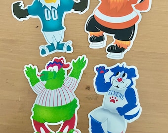 May include: Four cartoon mascots representing different sports teams. The mascots are a green and white creature with a red baseball cap, a blue and white dog with the word "SIXERS" on its jersey, a white eagle with a blue jersey and the number "00" on it, and an orange and white creature with a red beard.