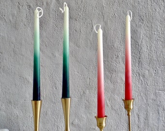 Könnte beinhalten: Vier Ombre-Kerzen in Grün, Grün, Rosa und Rosa auf goldenen Kerzenständern. Die Kerzen stehen auf einer weißen Oberfläche.