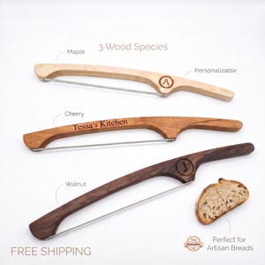 May include: Three wooden bread lames with metal blades, shown in maple, cherry, and walnut. The maple handle features a circular monogram with the letter A, the cherry handle is engraved with Tessa's Kitchen, and the walnut handle has a J monogram.