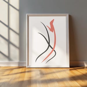 Könnte beinhalten: Gerahmter abstrakter Kunstdruck mit minimalistischem Design. Das Kunstwerk zeigt eine korallenfarbene Form und schwarze geschwungene Linien auf weißem Hintergrund. Der gerahmte Druck lehnt an einer grauen Wand, mit einem Holzboden im Vordergrund.