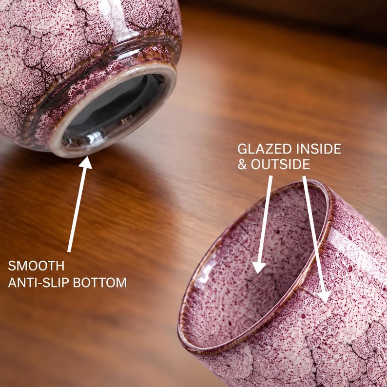 Pode incluir: Duas ch&aacute;venas de cer&acirc;mica com um acabamento de esmalte craquelado salpicado em roxo e branco. As ch&aacute;venas t&ecirc;m uma base lisa antiderrapante e s&atilde;o esmaltadas por dentro e por fora. O texto indica: SMOOTH ANTI-SLIP BOTTOM e GLAZED INSIDE & OUTSIDE.