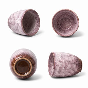 Pode incluir: Uma ch&aacute;vena de cer&acirc;mica mostrada de quatro &acirc;ngulos, com um esmalte salpicado em lavanda e branco com textura rachada. O exterior tem um padr&atilde;o recortado, enquanto o interior e a base apresentam um acabamento castanho escuro liso e brilhante.