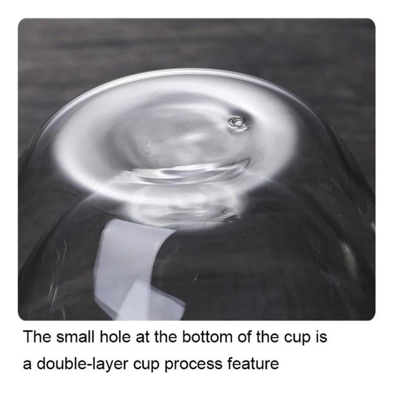May include: A clear glass cup featuring a small, circular hole at the bottom center. The text below the cup states: The small hole at the bottom of the cup is a double-layer cup process feature. The cup is made of transparent glass material.