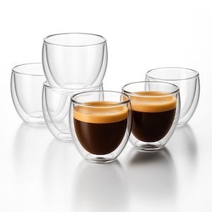 May include: Six clear, double-walled glass coffee cups. Two cups are filled with dark coffee and a layer of crema. The other four cups are empty. The cups are arranged on a white surface.