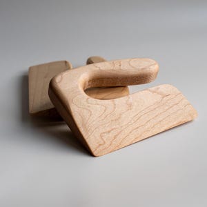 May include: Two wooden dough scrapers, one with a handle and one without, made of light brown wood.