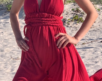 Puede incluir: Un vestido rojo maxi con tirantes y un cinturón de cuerda trenzada. El vestido está hecho de una tela suave y fluida y tiene un ajuste holgado.