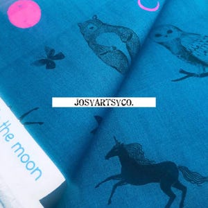 May include: Teal fabric with black illustrations of a unicorn, owl, squirrel, and butterfly, along with a pink circle and the text "to the moon". The brand name "JOSYARTSYCO." is also visible.