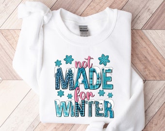 May include: White sweatshirt with the text "not made for winter" in blue and pink letters with snowflake and plaid patterns.