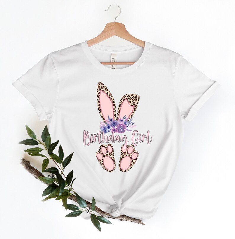 K&ouml;nnte beinhalten: Wei&szlig;es T-Shirt mit einem pinkfarbenen und braunen Hasenohren-Design und dem Text "Birthday Girl".