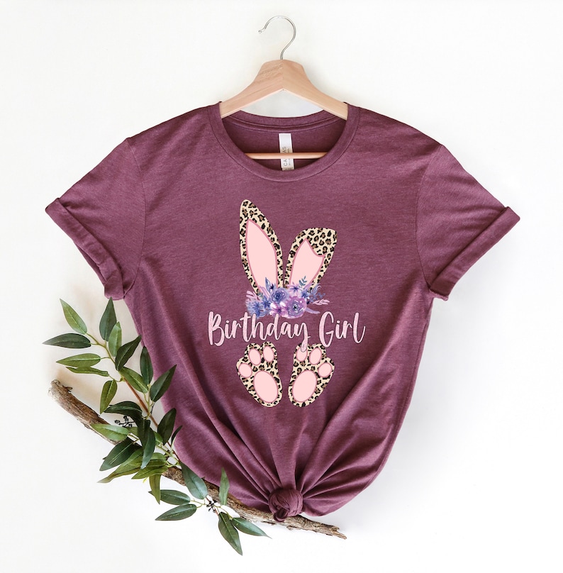 K&ouml;nnte beinhalten: Ein maroonfarbenes T-Shirt mit einem pinkfarbenen und braunen Hasen-Design und dem Text "Birthday Girl".