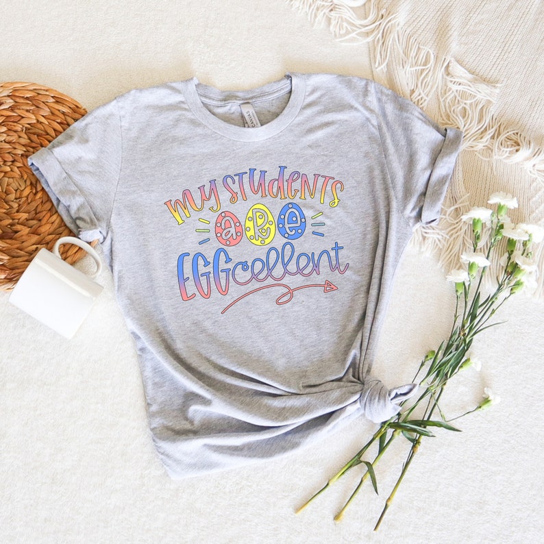 May include: Gray t-shirt with the text "My Students are Eggcellent" in rainbow colors with a stylized egg design.