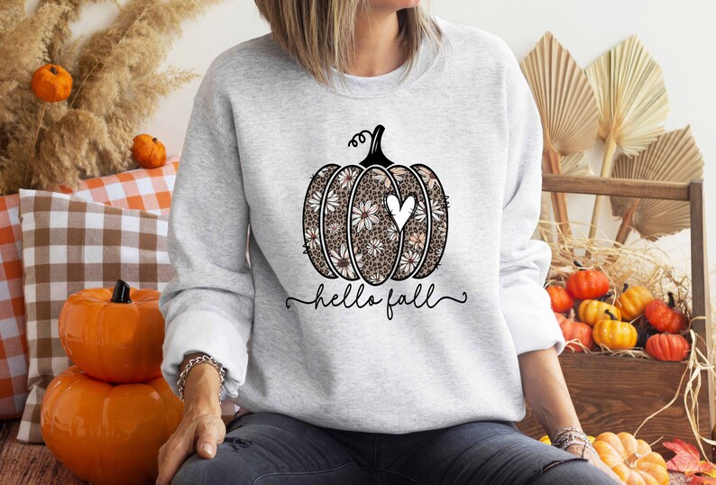 Puede incluir: Una sudadera gris con un dise&ntilde;o de calabaza floral y el texto "hello fall".