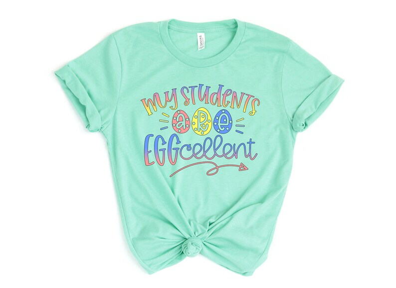 May include: A light green t-shirt with the text "My Students are Eggcellent" in rainbow colors. The text includes three stylized eggs with the letters "A", "R", and "E" inside.