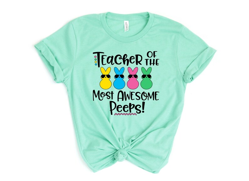 May include: Mint green t-shirt with the text "Teacher of the Most Awesome Peeps!" and four cartoon bunny figures wearing sunglasses in yellow, blue, pink, and green. The shirt is tied at the waist.