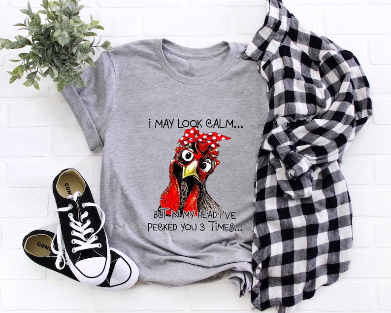 May include: Gray t-shirt with a red and white illustration of a chicken wearing a red bandana. The text on the shirt reads "I may look calm... But in my head I've pecked you 3 times..."