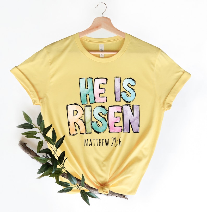 May include: Yellow t-shirt with a colorful graphic that says "He is Risen" with the scripture reference "Matthew 28:6" underneath.