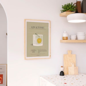 May include: A framed print featuring a Gin & Tonic cocktail illustration. The artwork displays a glass with a lemon slice and sprig of thyme, set against a light green background. The text "GIN & TONIC" is at the top.