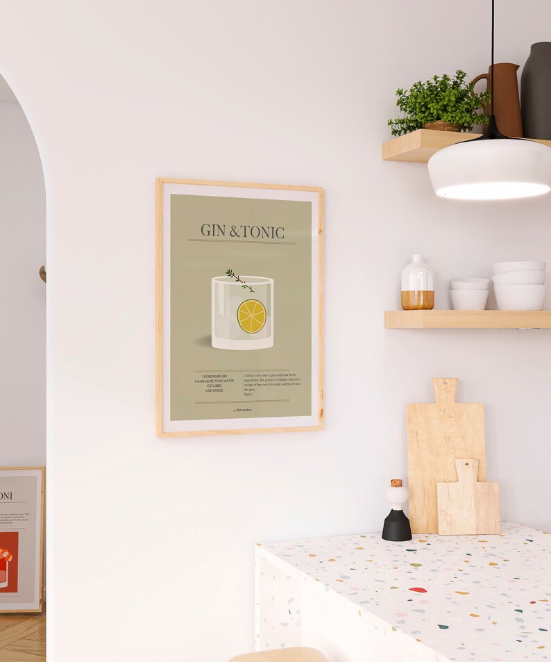 May include: A framed print featuring a Gin & Tonic cocktail illustration. The artwork displays a glass with a lemon slice and sprig of thyme, set against a light green background. The text "GIN & TONIC" is at the top.
