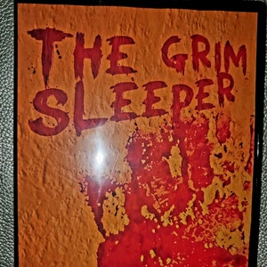 May include: A DVD cover with a red and orange background. The title "The Grim Sleeper" is written in red letters. A red handprint is in the center of the cover. The Lifetime logo is in the bottom left corner.