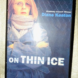 May include: A DVD cover featuring Academy Award winner Diane Keaton in a blue coat with a white scarf. The title of the movie is "On Thin Ice" and the text "Inspired by a true story" is also visible.