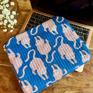 Könnte beinhalten: Eine blaue Laptoptasche mit einem weißen und roten Tigerdruck. Die Tasche ist gesteppt und hat einen Reißverschluss.