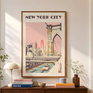 Retro travel poster print of the Brooklyn Bridge, New York City. Illustrated in warm pinks, yellow, and teals with a vintage flat-graphic style. The Manhattan skyline rises in the background beneath a blush sky. Shown framed in a walnut frame above a mid-century modern credenza in a warm, sunlit living room. Styled with art books, a mushroom lamp, and green branches.