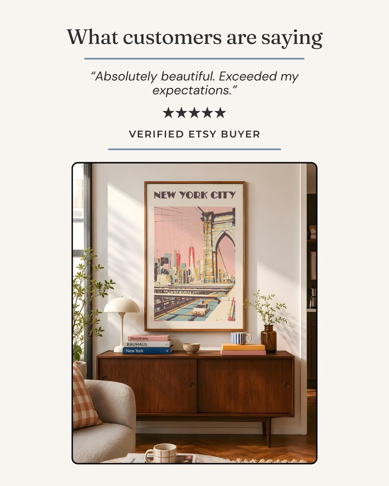 May include: A framed vertical wall art print titled NEW YORK CITY featuring a stylized illustration of the Brooklyn Bridge and city skyline in pink and blue tones, displayed above a dark wood sideboard with books, a lamp, and a small vase.